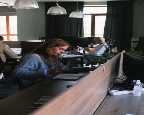 A well organized coworking desk with a person reading documents and natural light coming in